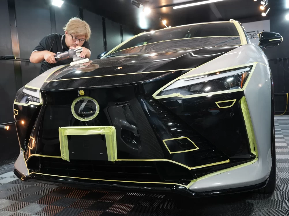 レクサスRZ550eのフロントマスクを丁寧に養生しボディ研磨を行う作業風景